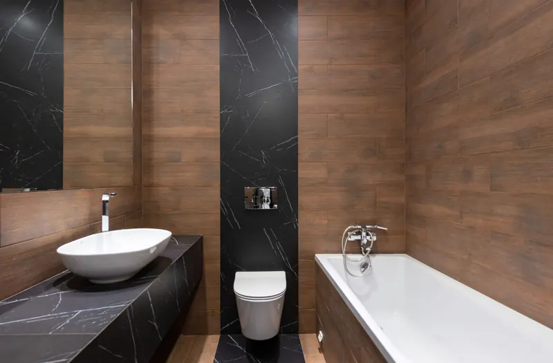 Modern bathroom with a basin on a dark worktop, a wall hung toilet and a bath