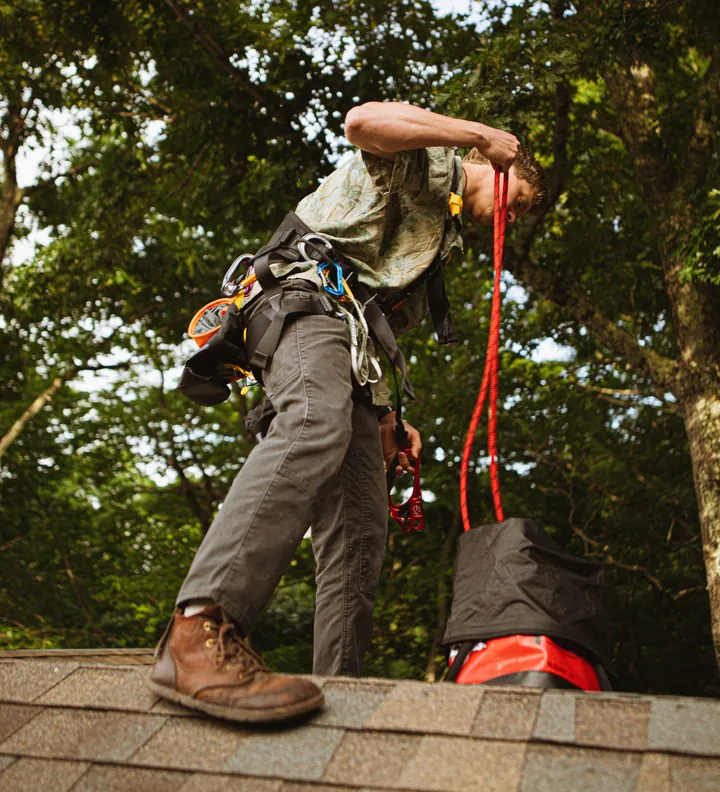 Roofer with a safety harness and rope up on a roof