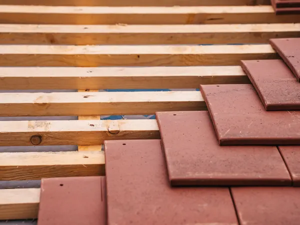 Red roof tiles being laid on new battens