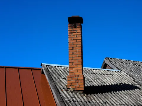 Murpipe mellom et rødt platetak og et grått tak