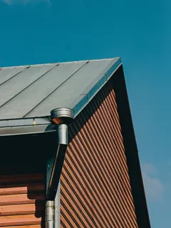 Takrenne og nedløp på hjørnet av et trehus med platetak