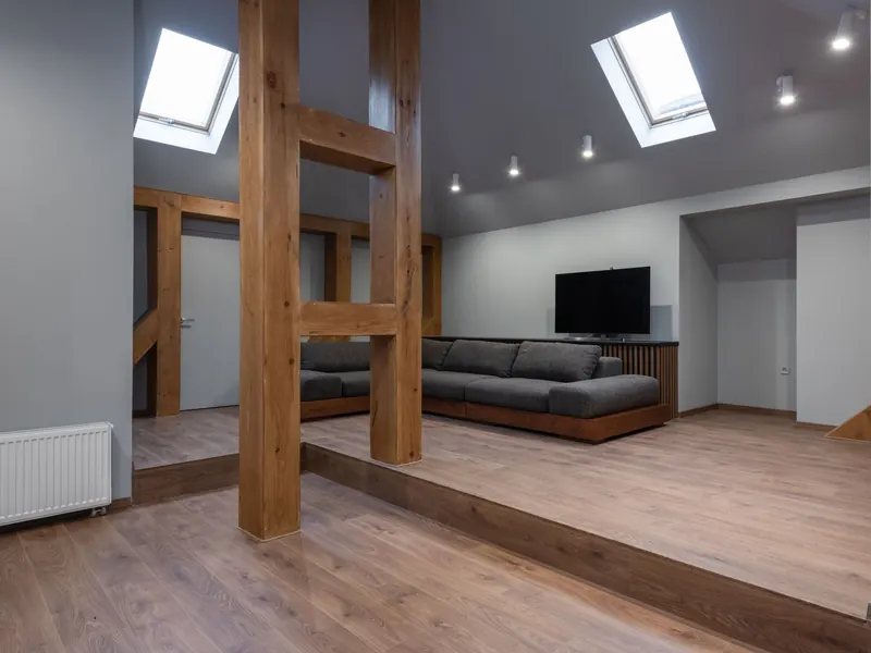 Ombygd loft med synlige stolper og bjelker i tre, takvinduer og sofa