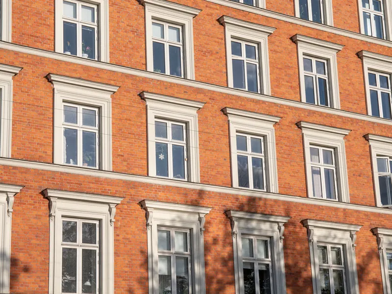 Restaurert teglfasade på eldre bygård med hvite vindusomramminger